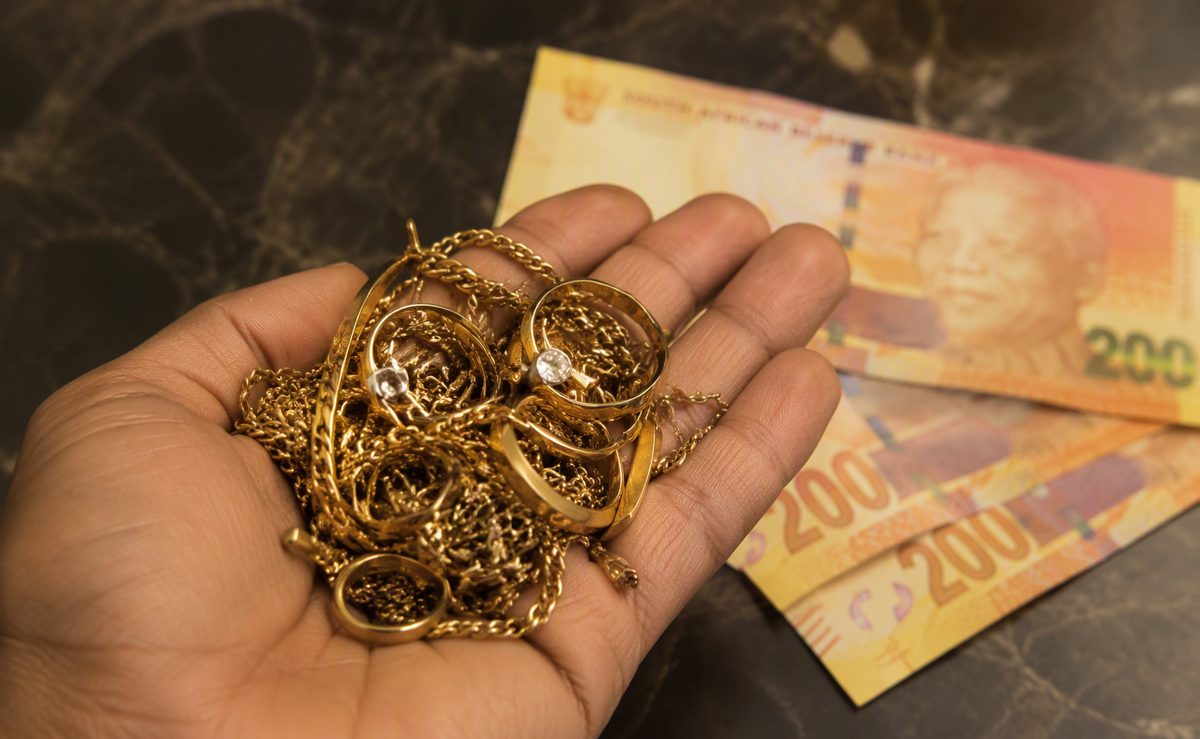 Cash for gold - hand holding broken gold chains and scrap gold jewellery